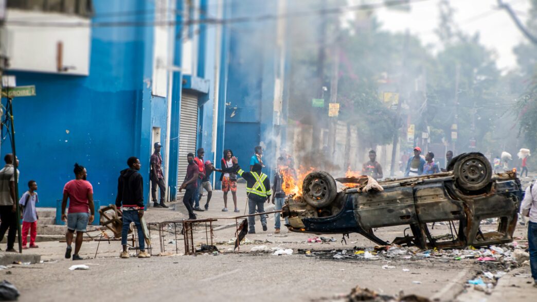 Des manifestants expriment leur colère en brûlant une voiture devant un poste de police en Haïti. Les tensions s'intensifient dans le pays, reflétant les défis auxquels la société haïtienne est confrontée. Crédit Photo : Carlin Trezil
