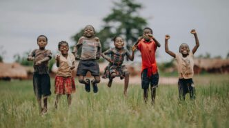 Des enfants sautent et rient dans un champ, incarnant la joie, l’espoir et la liberté que chaque enfant mérite en cette Journée dédiée à l’enfance.