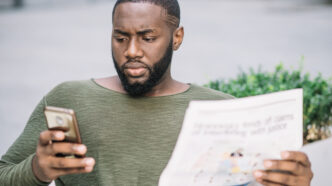 Homme sérieux avec journal en utilisant un smartphone