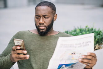 Homme sérieux avec journal en utilisant un smartphone