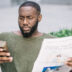 Homme sérieux avec journal en utilisant un smartphone